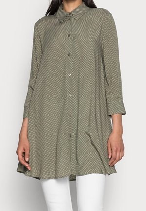 Camicia verde oliva con colletto, maniche a tre quarti e pois bianchi. Tessuto morbido con orlo leggermente svasato.