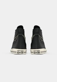 Sneaker alte nere realizzate in pelle testurizzata, con dettagli in catena metallica ai lati e una suola in gomma bianca a contrasto.