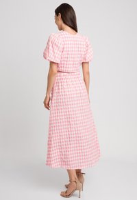 Różowo-biała sukienka w kratę z bufkami, wcięciem w talii i zwiewnym krojem maxi. Gładka tekstura i długość sięgająca kostek.