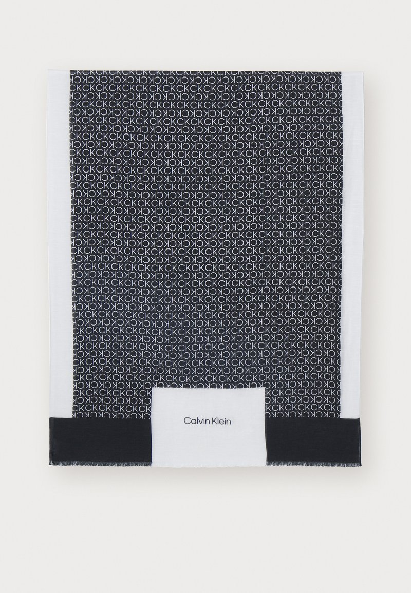 Sciarpa nera con un motivo a cerchi ripetuti in bianco. I bordi sono rifiniti con accenti neri e bianchi. Include un'etichetta Calvin Klein.