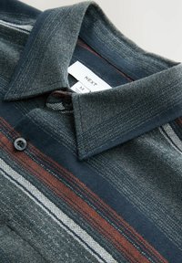 Camicia button-up con un tessuto navale testurizzato, caratterizzata da strisce a motivi rossi e bianchi, e un colletto standard. Etichetta visibile all'interno.
