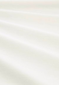 Textile blanc avec une surface lisse et légèrement texturée, présentant des plis et des ombres délicates, mettant en valeur sa fluidité douce et sa couleur.