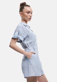 Stripet kortærmet jumpsuit i lys blå og hvid, med knapfront, blødt stof, rullede ærmer og to forlommer.