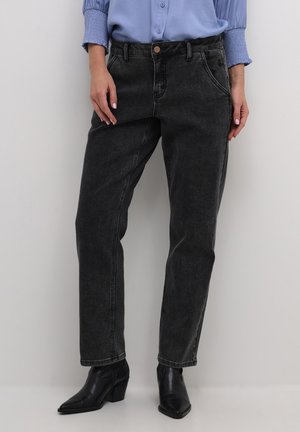Jeans in denim neri con una vestibilità rilassata, dettagliati con cuciture visibili, passanti per cintura e chiusura con bottone, abbinati a stivali neri con tacco.