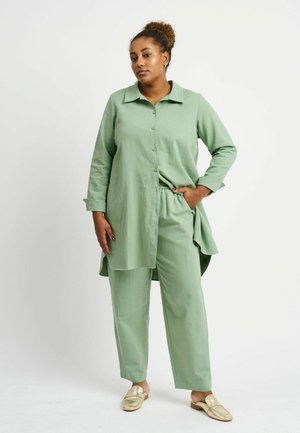 Mint green, lightweight button-up shirt with a collar, paired with matching tapered pants. Metallic gold slip-on shoes complete the outfit.