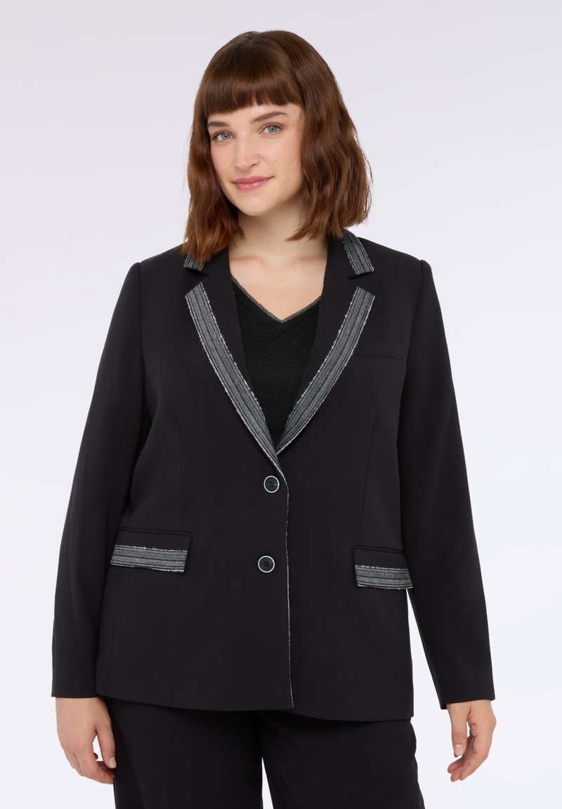 Sacou negru cu accente argintii pe guler și buzunare, două butoane și o croială ajustată, realizat dintr-un material ușor.