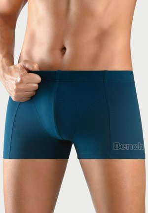 Navy blue boxer trunks made of stretch fabric, featuring a snug fit, seamless design, and a logo on the lower right side.