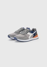 Gray athletic shoes with mesh and suede materials, navy and white accents, orange heel, textured outsole, and flat laces.