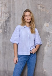 Blauw-wit gestreept overhemd met knoopsluiting en opgeblazen mouwen, gecombineerd met een blauwe spijkerbroek. Gladde stof met een ontspannen pasvorm en een casual ontwerp.