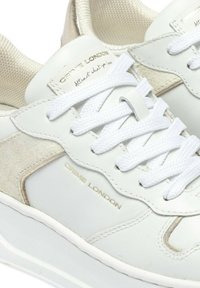 Sneakers bianchi in pelle con accenti in suede beige, linguetta in mesh testurizzato e lacci bianchi. Presentano il nome del marchio impresso in oro.