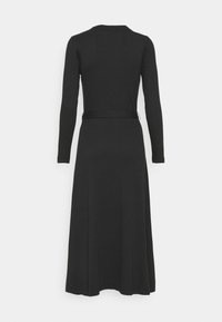 Abito lungo nero a maniche lunghe con scollatura rotonda e vita aderente, che si allarga fino a un orlo al ginocchio. Tessuto morbido e elasticizzato senza motivi visibili.