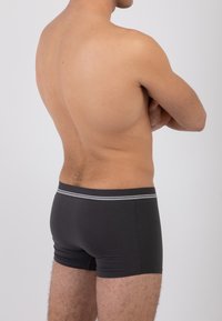 Boxer da uomo neri realizzati in tessuto morbido, dotati di un elastico a contrasto in vita con una striscia grigia, mostrati da una vista laterale.