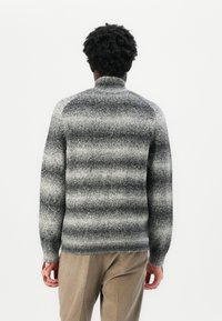 Pull en maille gris avec un col montant, présentant un motif rayé dégradé du gris foncé au gris clair. Finition texturée, coupe décontractée et manches longues.