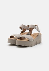 Gray platform sandals with a textured upper, open toe, and adjustable ankle straps. Thick, ridged sole for enhanced stability.