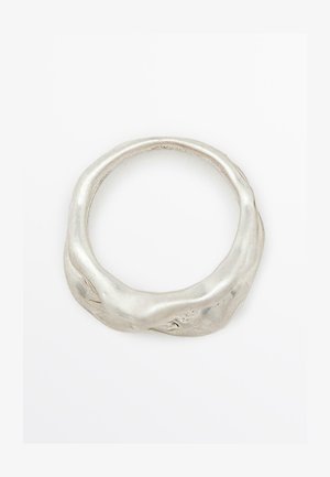 Zilveren ring met een ongelijkmatige, textuurachtige oppervlakte en een afgeronde, organische vorm. Gepolijste afwerking versterkt het metalen uiterlijk.