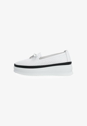 Biały sneaker typu slip-on z perforowanym wzorem, czarną lamówką wokół podeszwy, grubą białą platformą oraz małym dekoracyjnym metalowym detalem na wierzchu.