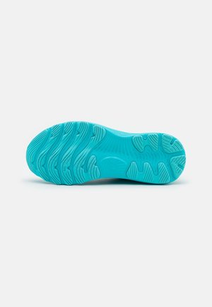 Semelle d'une chaussure de sport turquoise vif avec des motifs incurvés et des zones de préhension texturées sur un fond blanc uni.