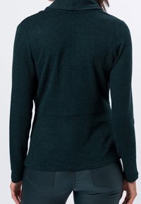 Sudadera de polar verde oscuro con cuello alto, mangas largas y un dobladillo curvado. Textura suave con un acabado liso y sin patrones visibles.
