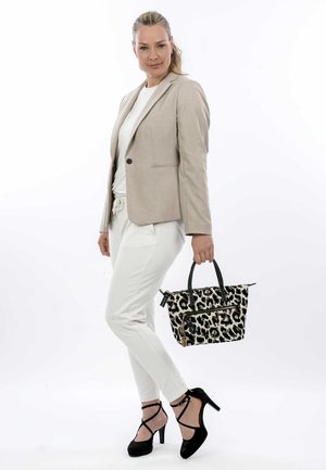 Tijgerprint tas met zwarte handvatten, met rits afgewerkte vakken en een gestructureerde vorm. Model draagt een beige blazer, witte top en witte broek.