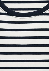 Lähikuva tummansinisestä ja valkoisesta vaakasuorasta kankaasta, jossa on tummansininen ribattua ympäri päätä oleva kaulus.