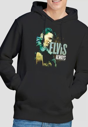Person trägt schwarzen Hoodie mit Grafik von Elvis Presley, der Gitarre spielt, und dem Text "ELVIS ALWAYS THE ORIGINAL" auf der Vorderseite.