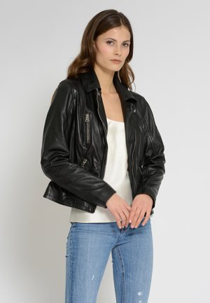 Schwarze Lederjacke mit taillierter Passform, ausgestattet mit Reißverschlusstaschen und einem eingekerbten Kragen. Getragen über einem weißen Oberteil und hellblauen Jeans.