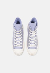 Hoge sneakers van licht lavendel stof met witte veters en rubberen zolen. Kenmerkt zich door een ronde neus en een gevoerde enkel voor comfort.