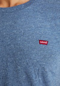 Μπλε βαμβακερό t-shirt με στρογγυλή λαιμόκοψη, διακριτική υφή και μικρή κόκκινη ετικέτα λογότυπου Levi's στην αριστερή περιοχή του στήθους.