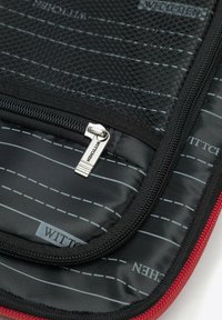 Czarna torba z zamkiem błyskawicznym do przechowywania, z siateczkowym wykończeniem, czerwonymi akcentami i w paski szarym wnętrzem. Posiada metalowe uchwyt do zamka z logo.