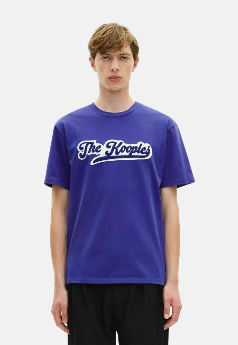 Blaues Baumwoll-T-Shirt mit kurzen Ärmeln, mit weißem "The Kooples"-Logo in Schriftzug auf der Vorderseite. Einfaches Rundhals-Design.