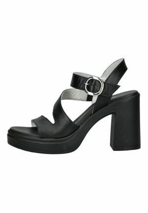 Sandalia negra de tacón alto con tacón grueso y bloque, punta abierta, tiras anchas y hebilla plateada en la correa del tobillo.