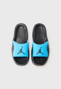 Sorte glidesandaler med en blå gummistrop, der har et sort Jumpman-logo. Tekstureret sort fodseng med et stribet mønster for bedre greb.
