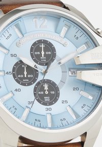 Orologio cronografo da polso con quadrante azzurro chiaro, tre quadranti neri, datario alle 3, indici delle ore argentati e cinturino in pelle marrone.