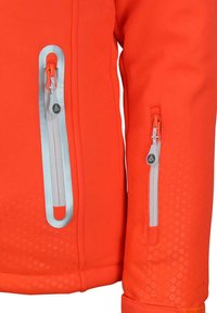 Veste orange vif avec une texture lisse, présentant des zippers réfléchissants, deux poches latérales zippées et une section inférieure à motifs.