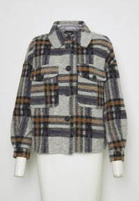 Grijze geruite jas met paarse, oranje en zwarte accenten. Voorzien van twee borstzakken, een kraag en knoopsluitingen. Zachte textuur.