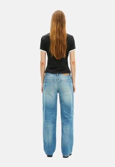 Plati kojinės šviesiai mėlynos džinsinės kelnės su išblukusiu apdaila ir penkių kišenių dizainu, derinamos su juodu viršumi, kuriame yra baltų akcentų ant rankovių.