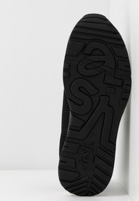 Semelle de chaussure noire avec une bande de roulement texturée et le mot « eas » intégré dans le design, affichant la taille numéro 37 sur un fond blanc.