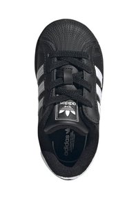 Čierne tenisky s bielymi tromi pásikmi, textúrovanou gumovou špičkou, šnúrkou na zaväzovanie, polstrovaným jazykom a mäkkou textíliou vo vnútri.