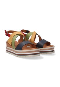 Multicolor leather wedge sandals featuring black, yellow, green, and red straps with an adjustable buckle and textured white sole with stripes.