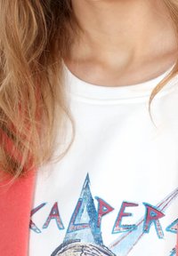 Bílá tričko s grafickým potiskem, na kterém jsou modrý a červený nápis "KALPERS" a design hory. Měkká látka s kulatým výstřihem.