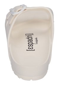 White slip-on sandal featuring a textured sole, smooth upper, and a small adjustable strap. The interior displays a printed brand name.