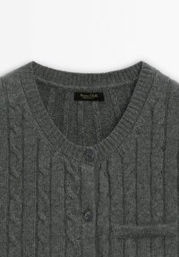 Graue Strickjacke mit Zopfmuster, rundem Ausschnitt, zwei schwarzen Knöpfen und einer kleinen Tasche auf der linken Seite.