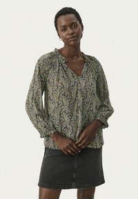 Blommönstrad blus i svart och grönt med V-nacke och volangkrage, med långa puffärmar och lätt tyg. Visad med en denimkjol.