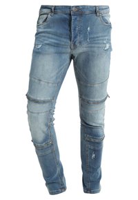 Ljusblå denimjeans med en sliten finish, med flera med dragkedjor och en avsmalnande bendesign.