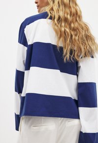 Long-sleeve top featuring horizontal navy and white stripes, made of soft cotton, with a relaxed fit and a rounded neckline.