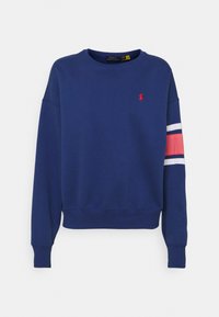 Tmavě modrá bavlněná mikina s kulatým výstřihem, žebrovanými manžetami a pasem. Na rukávech a logu má červené a bílé pruhy.