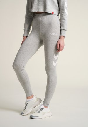 Grijze leggings van zachte stof met een gladde structuur, voorzien van een wit logo, een zij-chevronpatroon en een elastische tailleband.