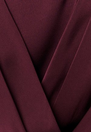 Tiefes Burgunderrot Stoff mit glatter, gefalteter Textur, die überlappende Schichten und sanfte Schatten erzeugt.