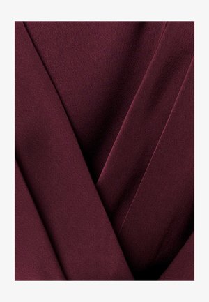 Gilus burgundiškas audinys su lygiu, sulankstytu paviršiumi, kuris sukuria persidengiančius sluoksnius ir minkštas šešėlines zonas.