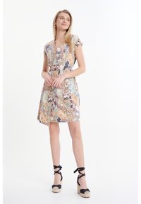 Lichtgewicht, multicolore jurk met korte mouwen, voorzien van een patchworkpatroon. Gecombineerd met marineblauwe espadrille-wedges met zwarte strikjes.